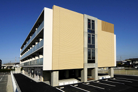 黄色いサイディング外装の介護施設の建物外観。駐車場を備えた近代的な4階建て
